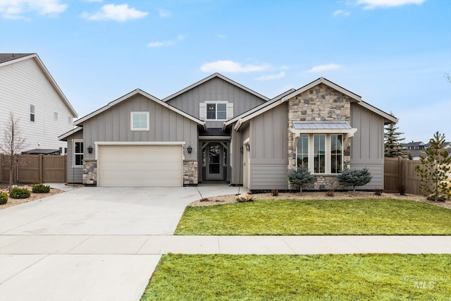 view of front facade with fence, driveway, stone siding, a front lawn, and board and batten siding