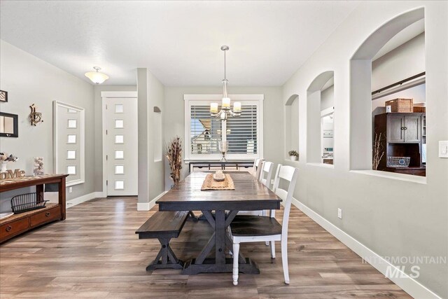 dining room featuring a notable chandelier, baseboards, and wood finished floors