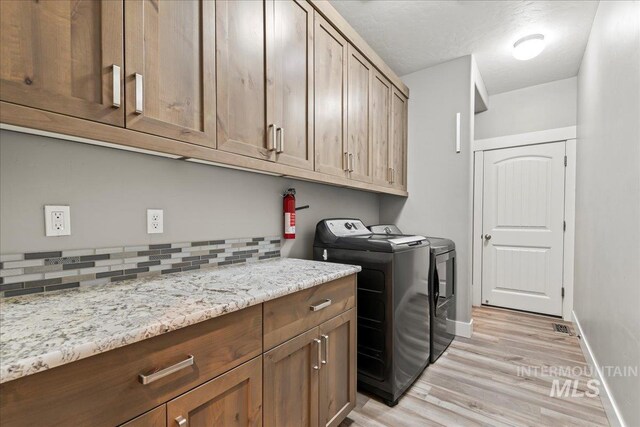 washroom featuring cabinet space, light wood-style flooring, baseboards, and separate washer and dryer