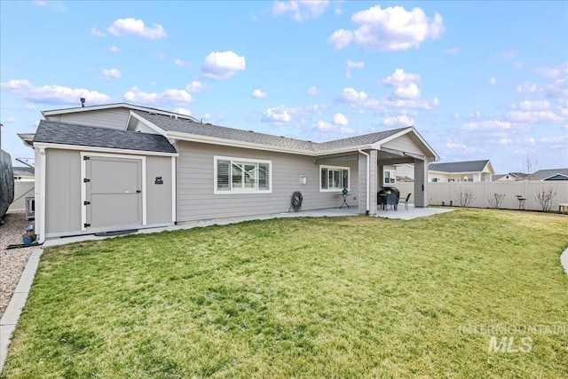 back of house featuring a yard, a patio, roof with shingles, and fence