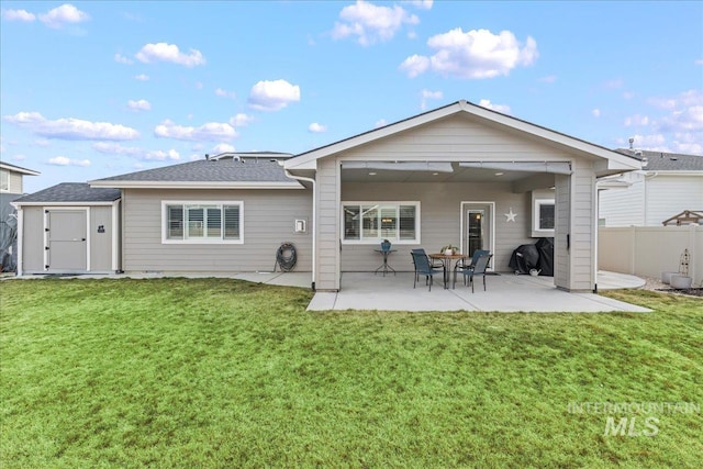 rear view of property featuring an outbuilding, fence, a yard, a storage shed, and a patio area