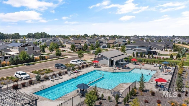 community pool featuring a residential view, a patio, and fence