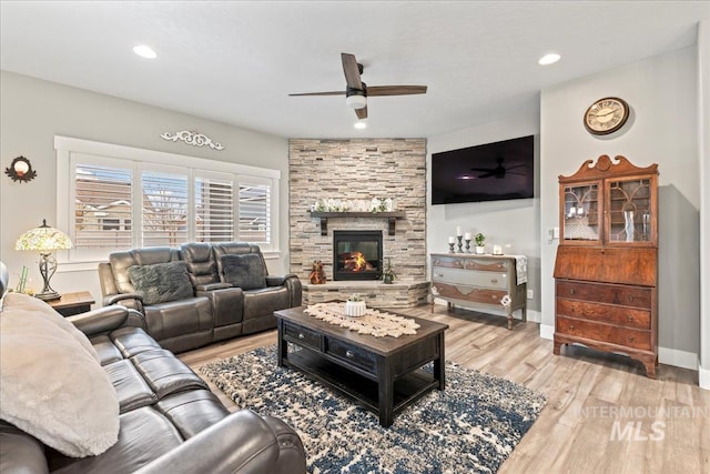 living area featuring ceiling fan, baseboards, light wood-type flooring, recessed lighting, and a fireplace