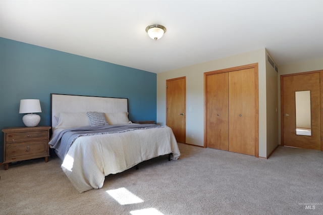 bedroom with light carpet and two closets