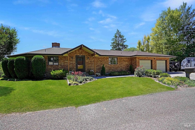 single story home featuring driveway, a chimney, an attached garage, a front lawn, and brick siding