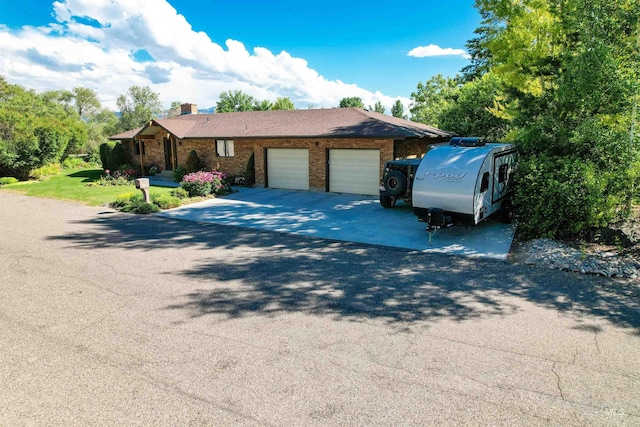 single story home with a garage, driveway, and brick siding