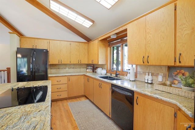 kitchen featuring tasteful backsplash, light wood-style flooring, vaulted ceiling, black appliances, and a sink