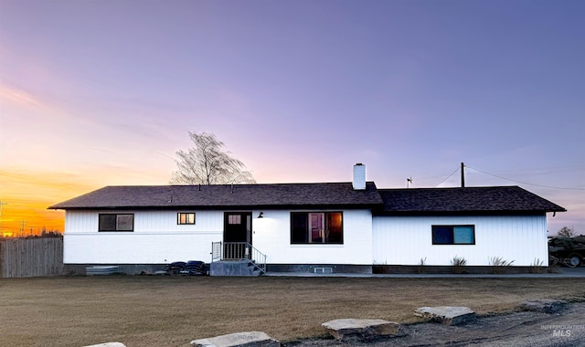 back of house featuring a chimney, roof with shingles, and fence