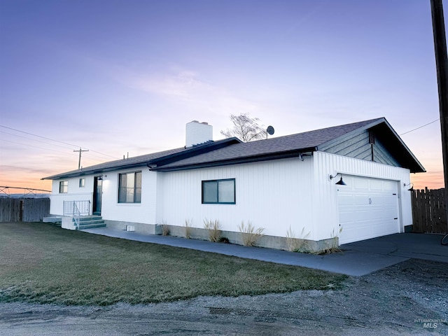 view of side of property with a garage, a yard, a chimney, and fence