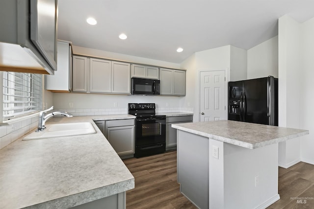 kitchen featuring dark wood finished floors, gray cabinetry, black appliances, and a sink