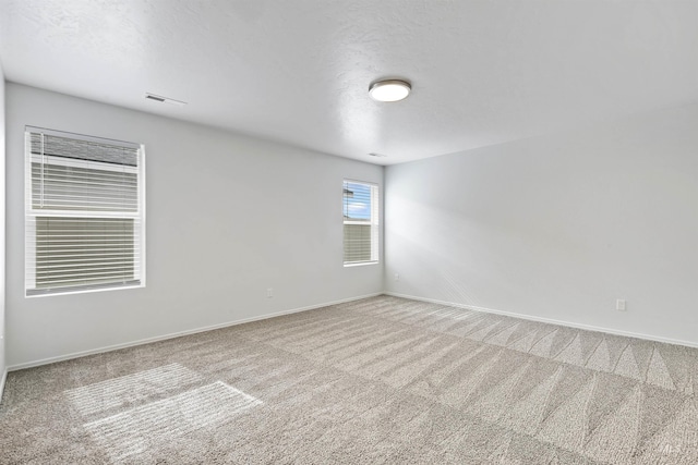 empty room featuring a textured ceiling, baseboards, and carpet floors