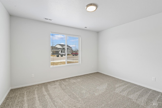 empty room with carpet flooring, baseboards, and visible vents