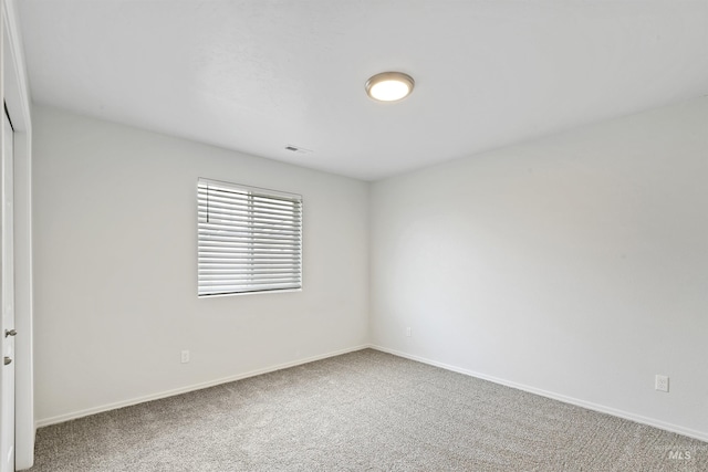 spare room featuring carpet flooring and baseboards