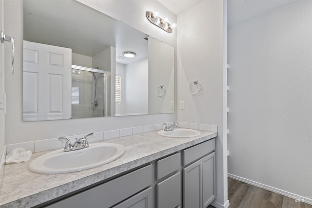 full bath featuring a sink, wood finished floors, a stall shower, and double vanity