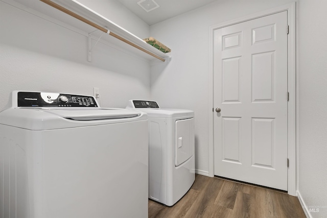 clothes washing area featuring visible vents, washer and dryer, laundry area, baseboards, and dark wood-style flooring