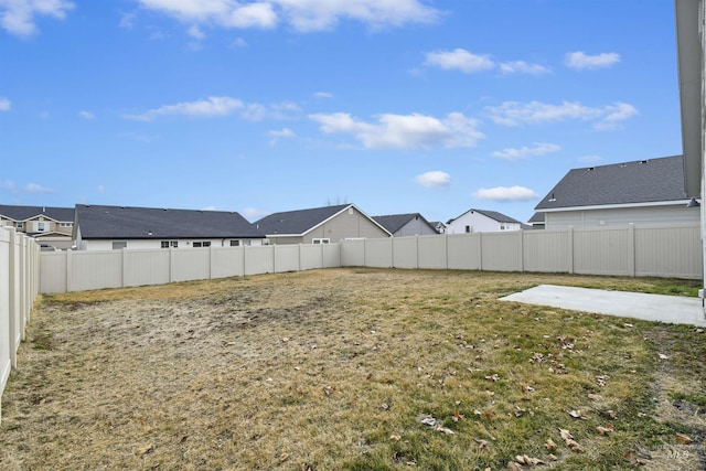 view of yard featuring a patio area, a fenced backyard, and a residential view