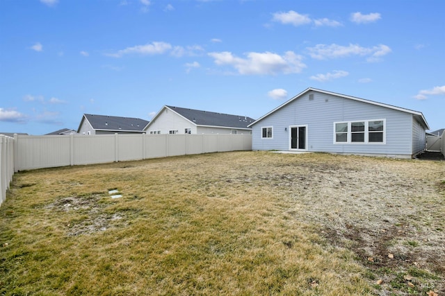 back of house with a fenced backyard and a lawn