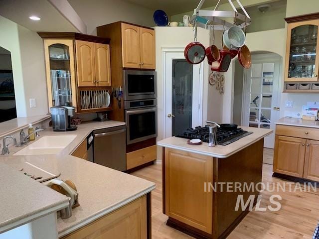 3997 W Harbor Point Dr, Meridian, ID 83646 - kitchen featuring stainless steel appliances, a sink, arched walkways, light countertops, and glass insert cabinets