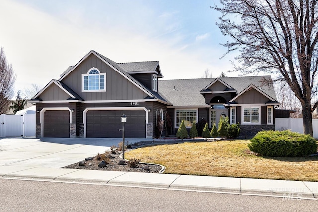 craftsman-style house featuring concrete driveway, a gate, fence, and stone siding