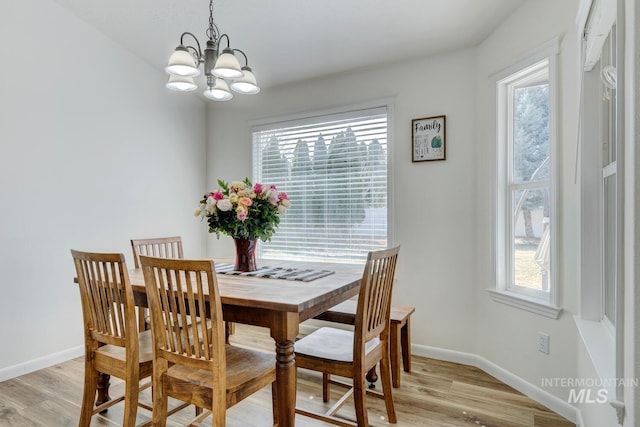 dining room with light wood-type flooring, baseboards, and a chandelier