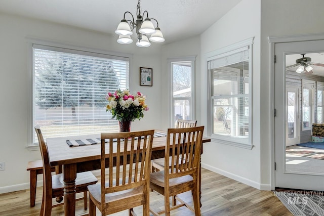 dining room featuring ceiling fan with notable chandelier, light wood-style floors, and baseboards