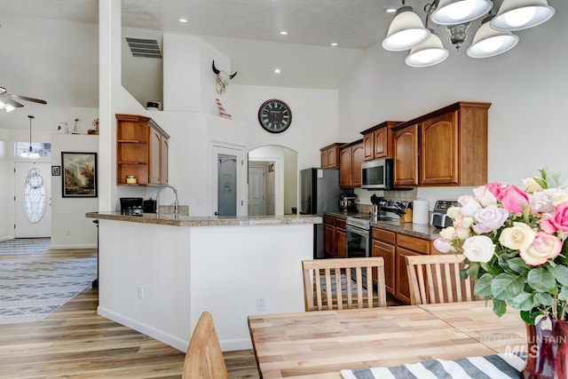 kitchen with visible vents, high vaulted ceiling, open shelves, arched walkways, and stainless steel appliances