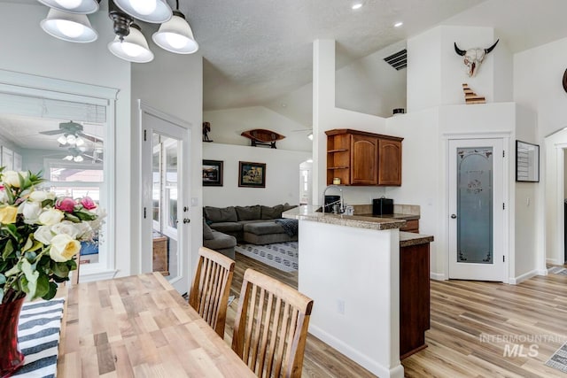 kitchen featuring a ceiling fan, open shelves, light wood-style flooring, a peninsula, and a textured ceiling