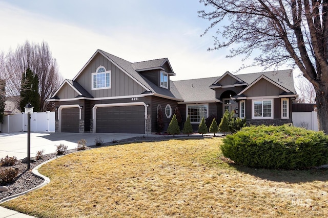 craftsman-style house featuring a garage, fence, stone siding, and driveway