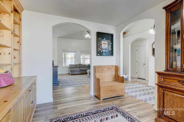 living area with a ceiling fan, arched walkways, and light wood finished floors