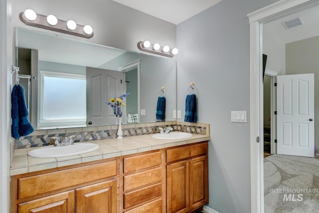 bathroom with double vanity, visible vents, and a sink