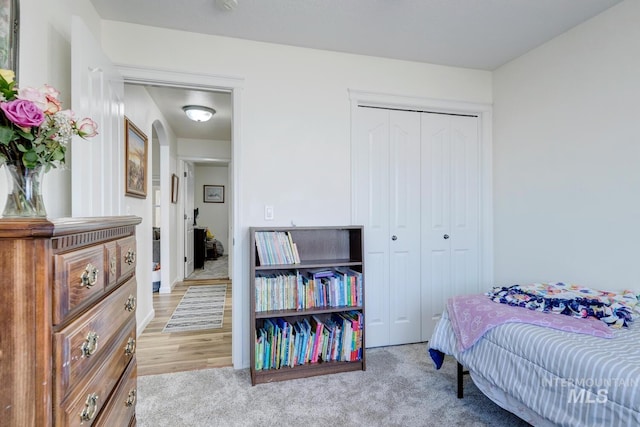 carpeted bedroom featuring a closet and arched walkways