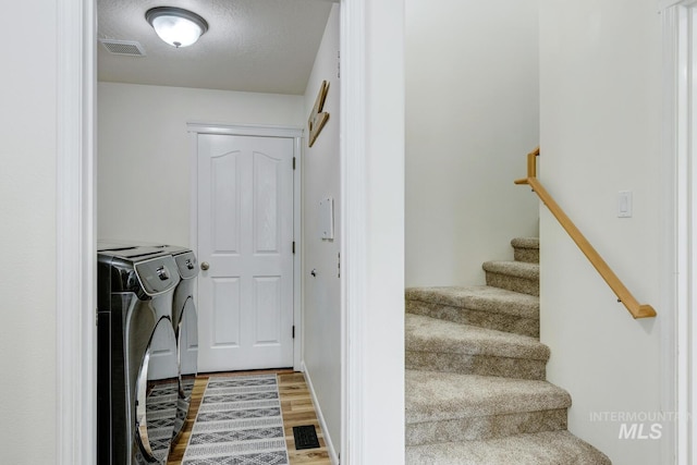 laundry area with visible vents, laundry area, a textured ceiling, washer and dryer, and light wood-type flooring