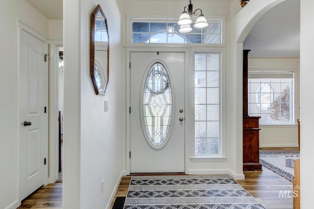 foyer entrance featuring plenty of natural light, arched walkways, and wood finished floors