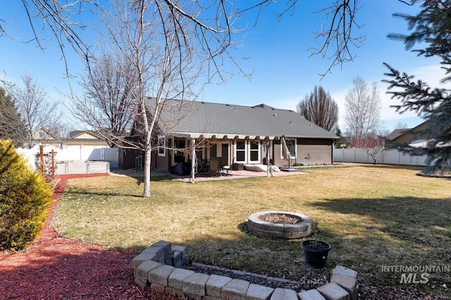 rear view of property featuring a patio, roof with shingles, a yard, a fenced backyard, and a fire pit