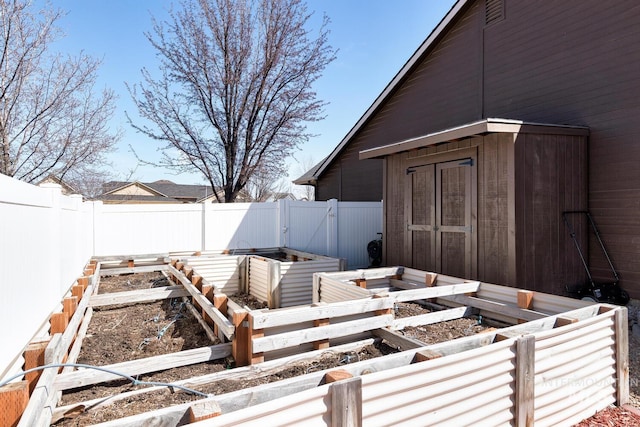 exterior space with an outdoor structure, a vegetable garden, a storage unit, and a fenced backyard