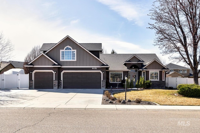 craftsman-style home featuring stone siding, driveway, fence, and a gate