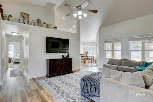 living room featuring light wood-style floors, a healthy amount of sunlight, visible vents, and baseboards