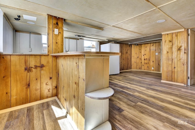 405 N 2nd E, Mountain Home, ID 83647 - below grade area featuring wood finished floors, wood walls, bar area, freestanding refrigerator, and baseboards