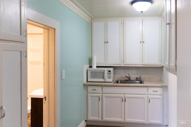 405 N 2nd E, Mountain Home, ID 83647 - kitchen featuring white microwave, a sink, white cabinets, and light countertops