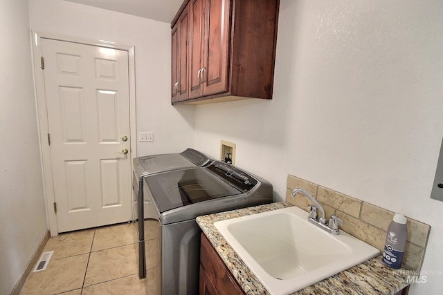 clothes washing area featuring cabinets, light tile patterned floors, sink, and washer and clothes dryer