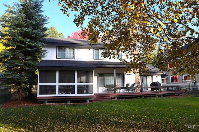 back of house featuring a wooden deck, a sunroom, and a yard