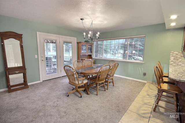 carpeted dining area featuring a chandelier, a textured ceiling, and a healthy amount of sunlight