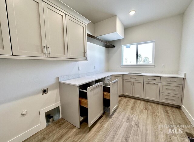 laundry area featuring electric dryer hookup, light hardwood / wood-style flooring, and cabinets