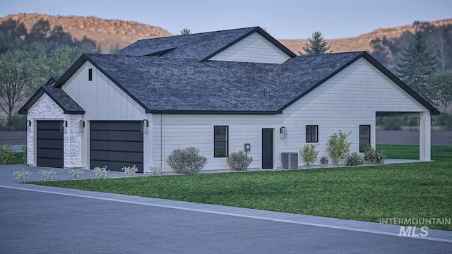 view of front of property featuring a garage, a yard, and central AC