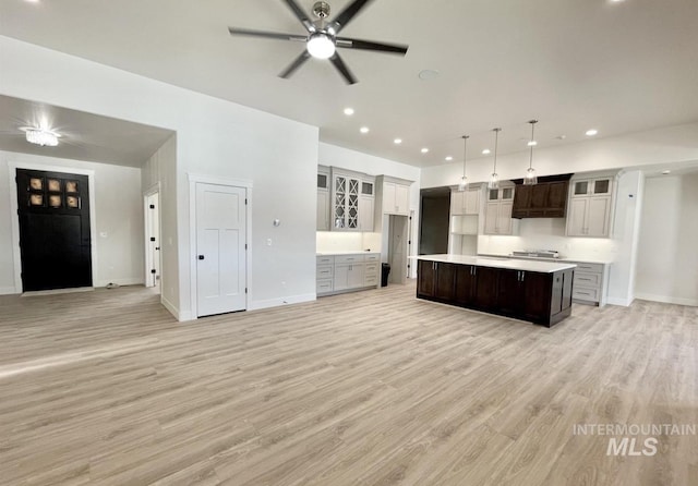 kitchen featuring premium range hood, ceiling fan, light hardwood / wood-style floors, a kitchen island, and hanging light fixtures