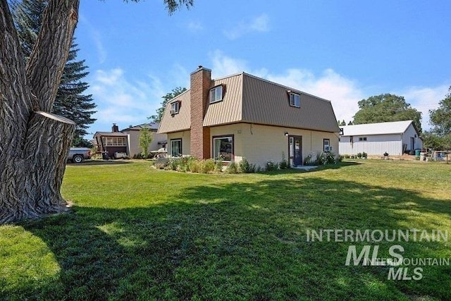 rear view of property with a gambrel roof, metal roof, a lawn, and a chimney