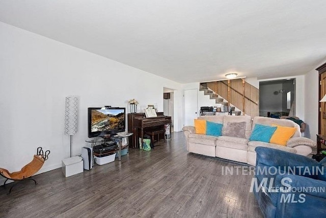 living room featuring dark wood-type flooring and stairs