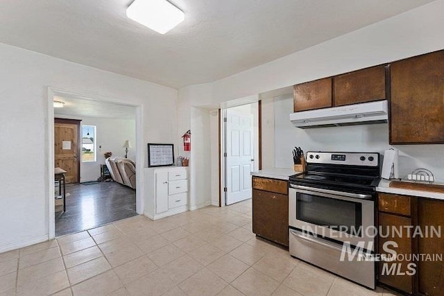 kitchen featuring under cabinet range hood, dark brown cabinetry, light countertops, and stainless steel electric stove