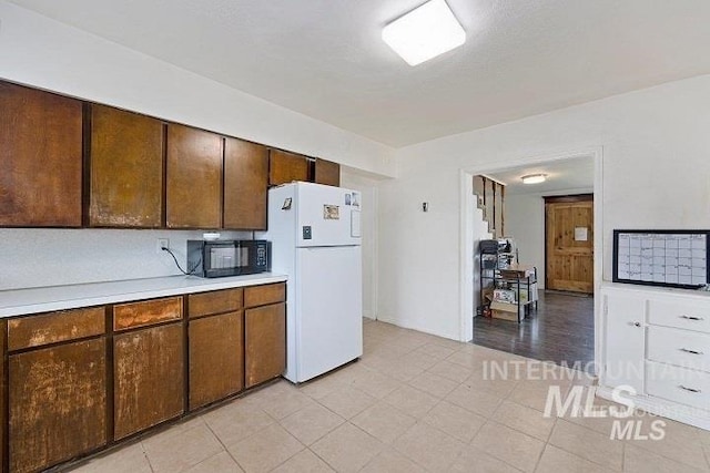 kitchen with freestanding refrigerator, light countertops, and black microwave