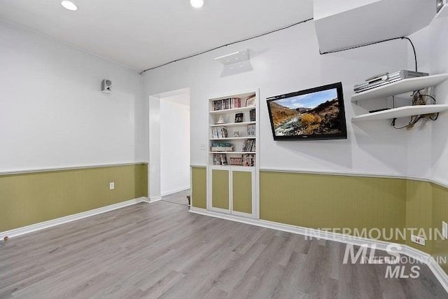 spare room with recessed lighting, built in shelves, wainscoting, and wood finished floors